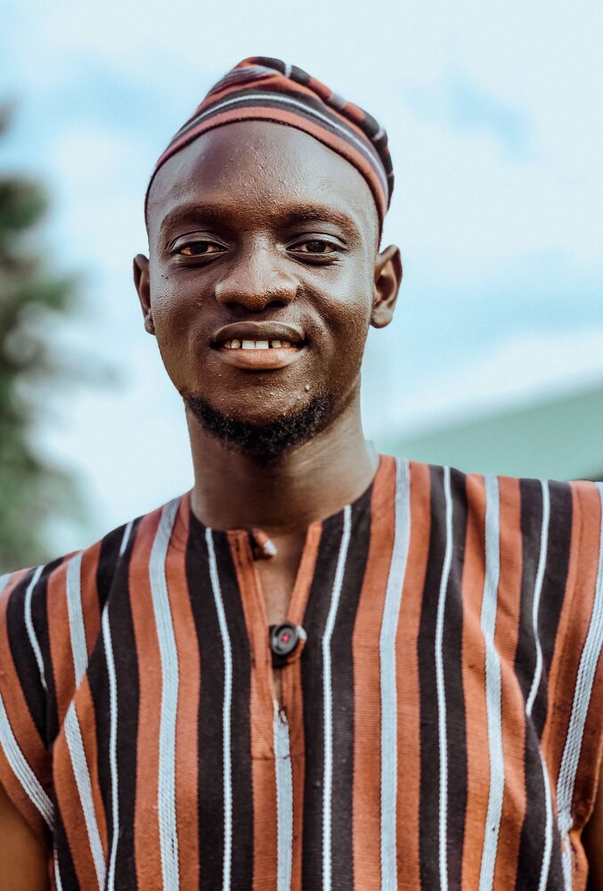 A Nigerian man smiling in traditional attire